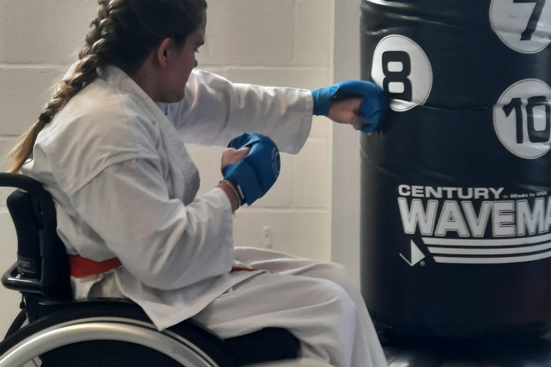 Photo of girl in a wheelchair punching a punchbag